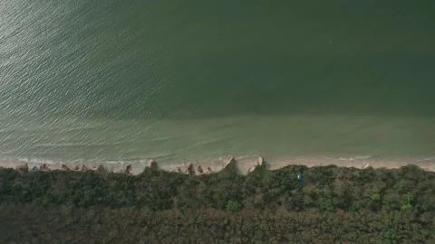 Aerial view of ocean waves beating against a rocky shore on a sandy tropical Stock Footage 156410244