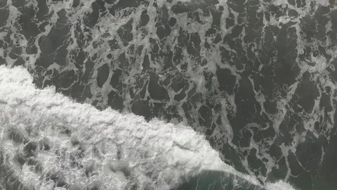 Aerial view of ocean waves breaking top down with foam onto beach Stock Footage 105986319