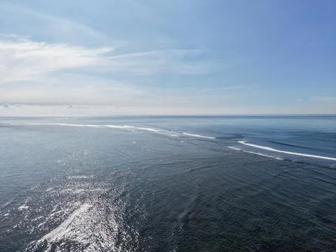 Aerial view of ocean waves breaking over a coral reef with sunlight Stock Photos
