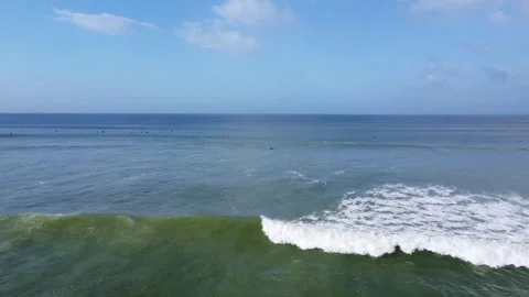 Aerial view of ocean waves crashing on a sunny day with a clear blue sky and Stock Footage 308975770