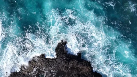 Aerial view of ocean waves crashing against rocky coastline, showcasing dynamic Video stock 341122401