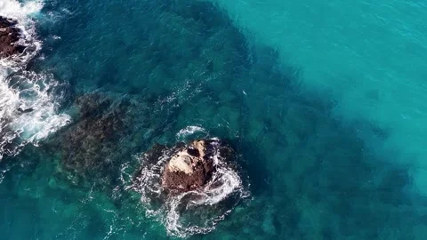 Aerial View of Ocean Waves Crashing Against Rocks in Turquoise Water Video stock 342574077