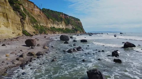 Aerial view of ocean waves crashing on rocky shoreline along steep cliffs Stock Footage 344440085