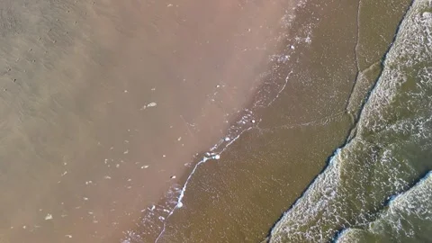 Aerial view of ocean waves gently rolling onto a sandy beach Stock Footage 309307783