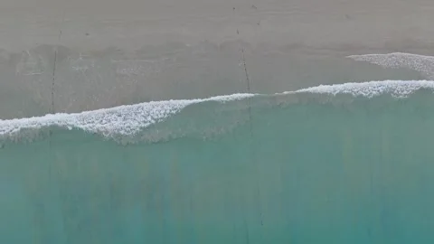 Aerial view of ocean waves gently crashing on sandy beach shoreline Vídeos de archivo 342312823