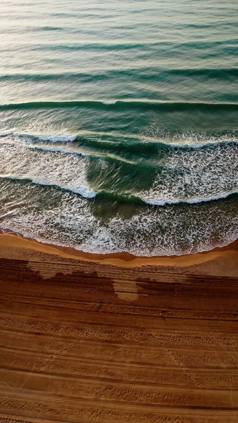 Aerial view of ocean waves hitting sandy beach Stock Footage 312217567