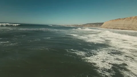 Aerial view of ocean waves hitting sandy beach with cliffs Stock Footage 339789618