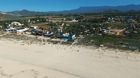 Aerial View of Ocean Waves, Rocky Mountains, and Sandy Beach with Greenery Stock Footage 297123473