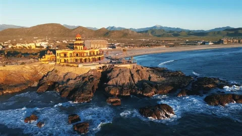 Aerial View of Ocean Waves, Rocky Mountains, and Sandy Beach with Greenery Stock Footage 297123716