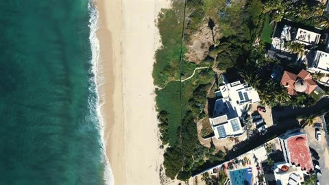 Aerial View of Ocean Waves, Rocky Mountains, and Sandy Beach with Greenery Stock Footage 297123733