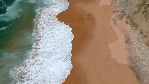 Aerial view of ocean waves in a sandy beach. Waves hit the shoreline. Stock Footage 94472446