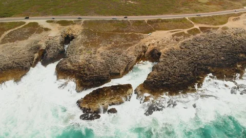 Aerial view ocean's waves crushing on rocky shore near picturesque road Video stock 107963443