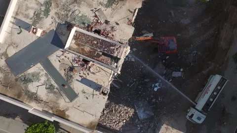 Aerial View: An old building crumbles as an excavator clears the site for new Vídeos de archivo 296038850