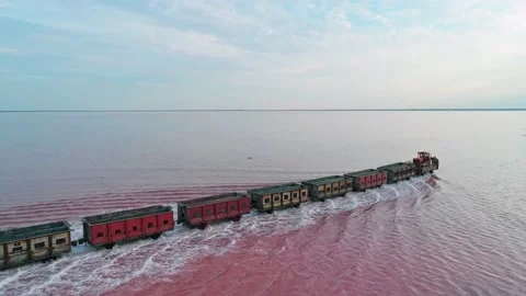 Aerial view of an old train rides on the railway laid in the water through the Stock Footage 231603174