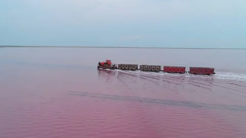 Aerial view of an old train rides on the railway laid in the water through the Stock Footage 231603200