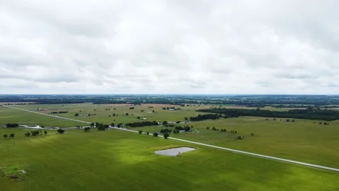 Aerial view of open fields and road as minimal traffic passes Stock Footage 156411579