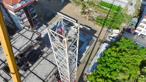 Aerial View: Operator climbs high ladders, assembling crane components with Vídeo Stock 296021812