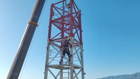 Aerial View: Operator works high above, mounting crane components and navigating Video stock 296022553