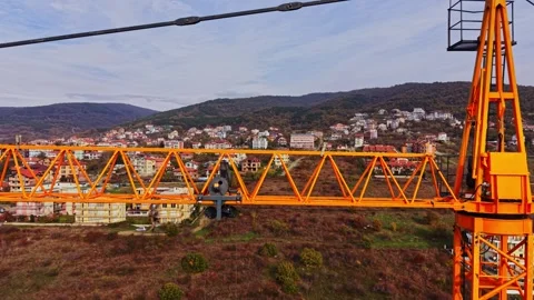 Aerial view of an orange construction crane overlooking a mountain village Stock Footage 324522130