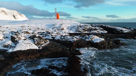 Aerial view of orange lighthouse on snowy coast in Iceland Stock Footage 337611974