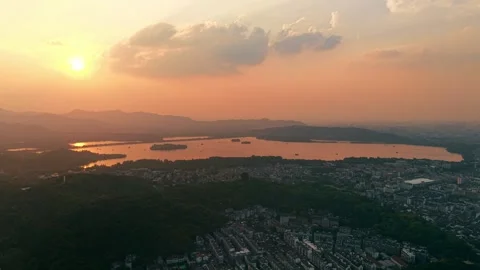 Aerial view of an orange sunset over West Lake and Hangzhou city with distant Stock Footage 317100058