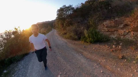 Aerial view, orbit around a man jogging on a scenic path on the cliff at sunset Stock Footage 107913169
