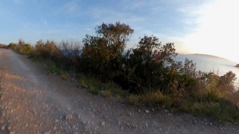 Aerial view, orbit around a man jogging on a scenic path on the cliff at sunset Stock Footage 107913171