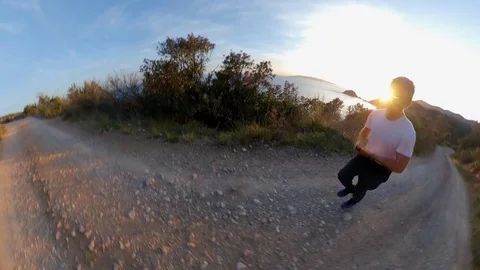 Aerial view, orbit around a man jogging on a scenic path on the cliff at sunset Stock Footage 107913172