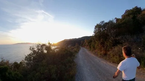 Aerial view, orbit around a man jogging on a scenic path on the cliff at sunset Stock Footage 107913484
