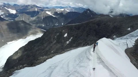 Aerial view orbiting around a group of people standing and hiking on snowy Stock Footage 307913386