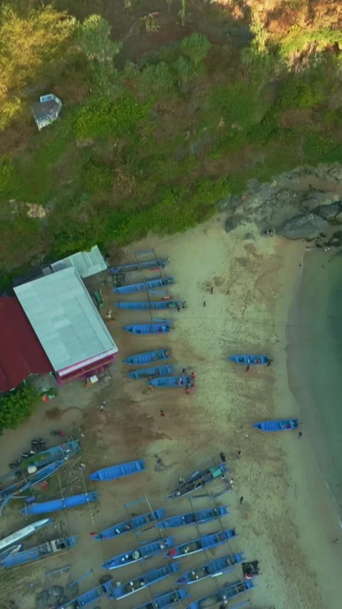 Aerial view of orderly rows of blue fishing boats arranged along a sandy tr.. Stock Footage 341543635