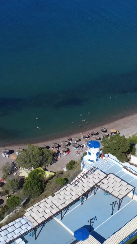 Aerial view of an organized sandy beach with a windmill on Greek island Vídeo Stock 344093657