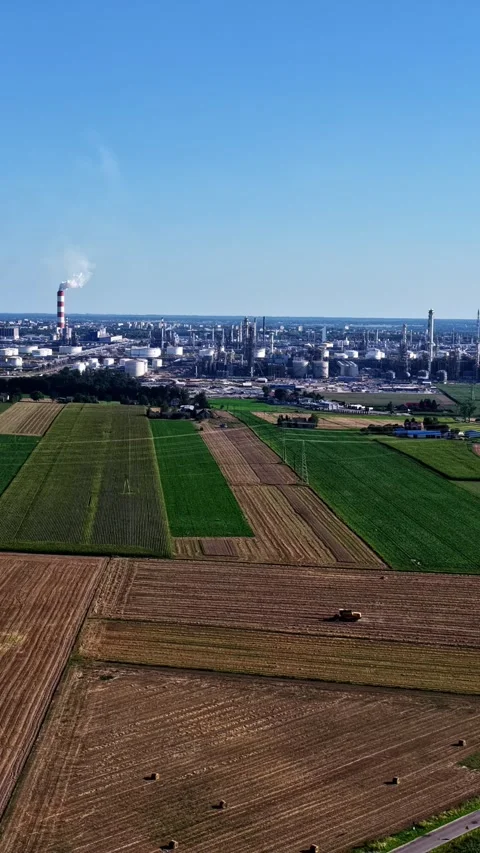 Aerial view of ORLEN Płock refinery in Poland beyond patchwork farmland, with Stock Footage 344521135