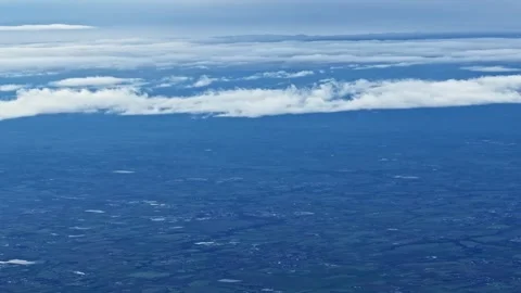 Aerial View Out of Plane Window of Clouds Over Blue Landscape Stock Footage 336126644