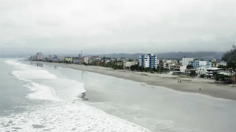 Aerial view over a beach lined with buildings on a cloudy day in Ecuador Video stock 146342178