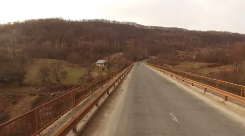Aerial view over bridge at sunset with motorcycle passing in scene Stock Footage 63018690