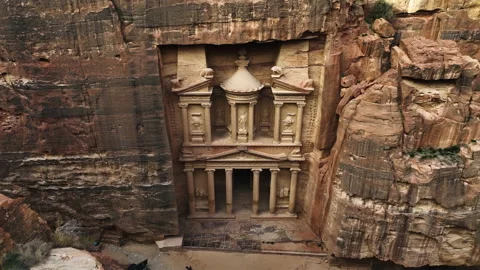 Aerial view over cliffs, tilting toward the Treasury, Al-Khazneh in Petra, Stock Footage 239421733