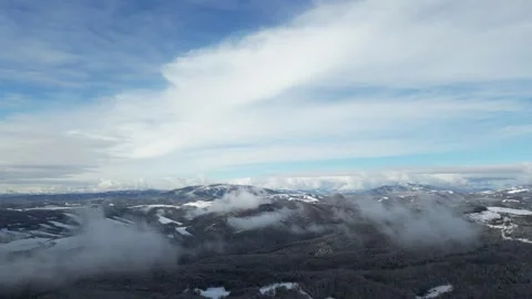 Aerial View Over Clouds with Snowy Forest and Winter Mountains Stock Footage 306223662