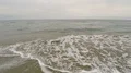 Aerial view over coastline, waves crashing onto the shore, throwing seaweed 4k or 4k+ Resolution