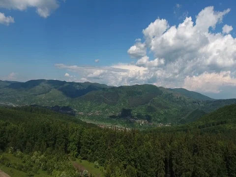 Aerial view over a forest and mountains with clouds rapidly moving Stock Footage 69433358