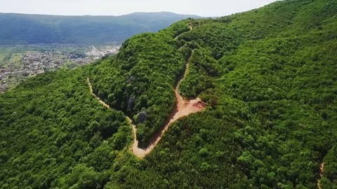 Aerial view over the forest in the mountains, road in the mountains Stock Footage 76507536