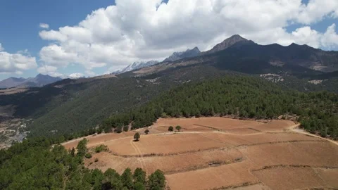 Aerial view over green mountain foothills and valley village in China Stock Footage 337884072
