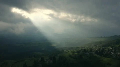 Aerial view over a mountain village illuminated by a ray of celestial light Stock Footage 132636634