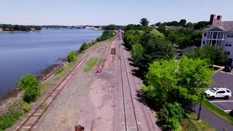 Aerial view over passenger tracks near an apartment complex and a river in Stock Footage 340045106