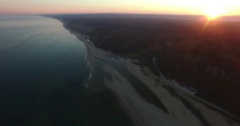 Aerial view over a river flowing into the sea at sunset Stock Footage 84267132