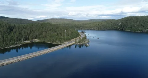 Aerial view over a road between, forest, a lake and mountains Stock Footage 113288519