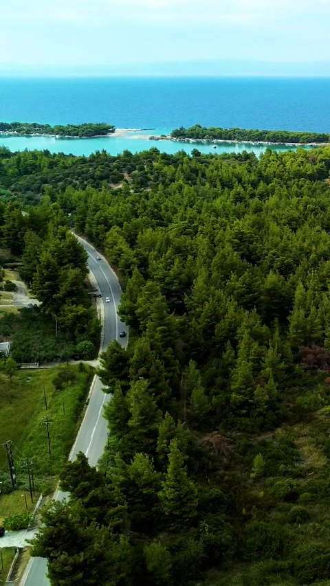 Aerial view over road in forest with sea in distance, Greece Stock Footage 342238507