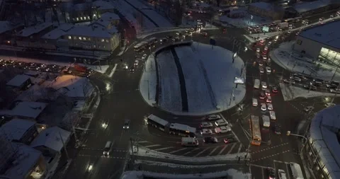 Aerial view over a roundabout covered in snow with traffic moving at night Stock Footage 261021175