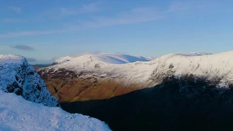 Aerial view over snow-covered fells at sunrise in the Lake District Stock Footage 345299784