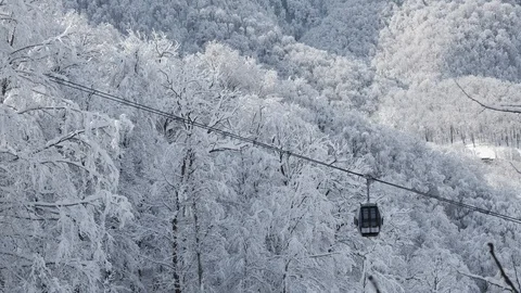 Aerial view over snowy mountain ridge valley with clouds, cable car lifting. Video stock 101537747